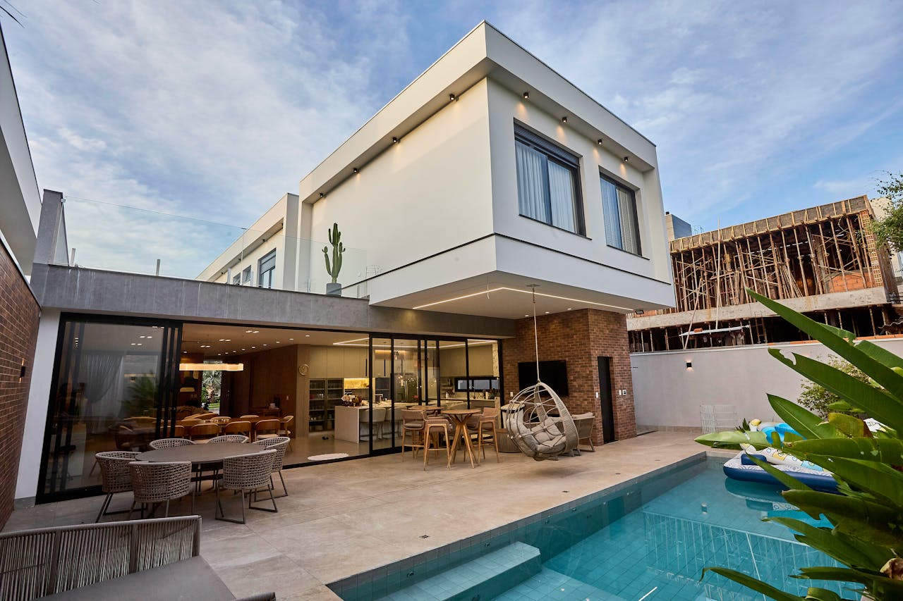 about-us-02 A contemporary luxury home with a pool and outdoor seating, showcasing modern architecture.